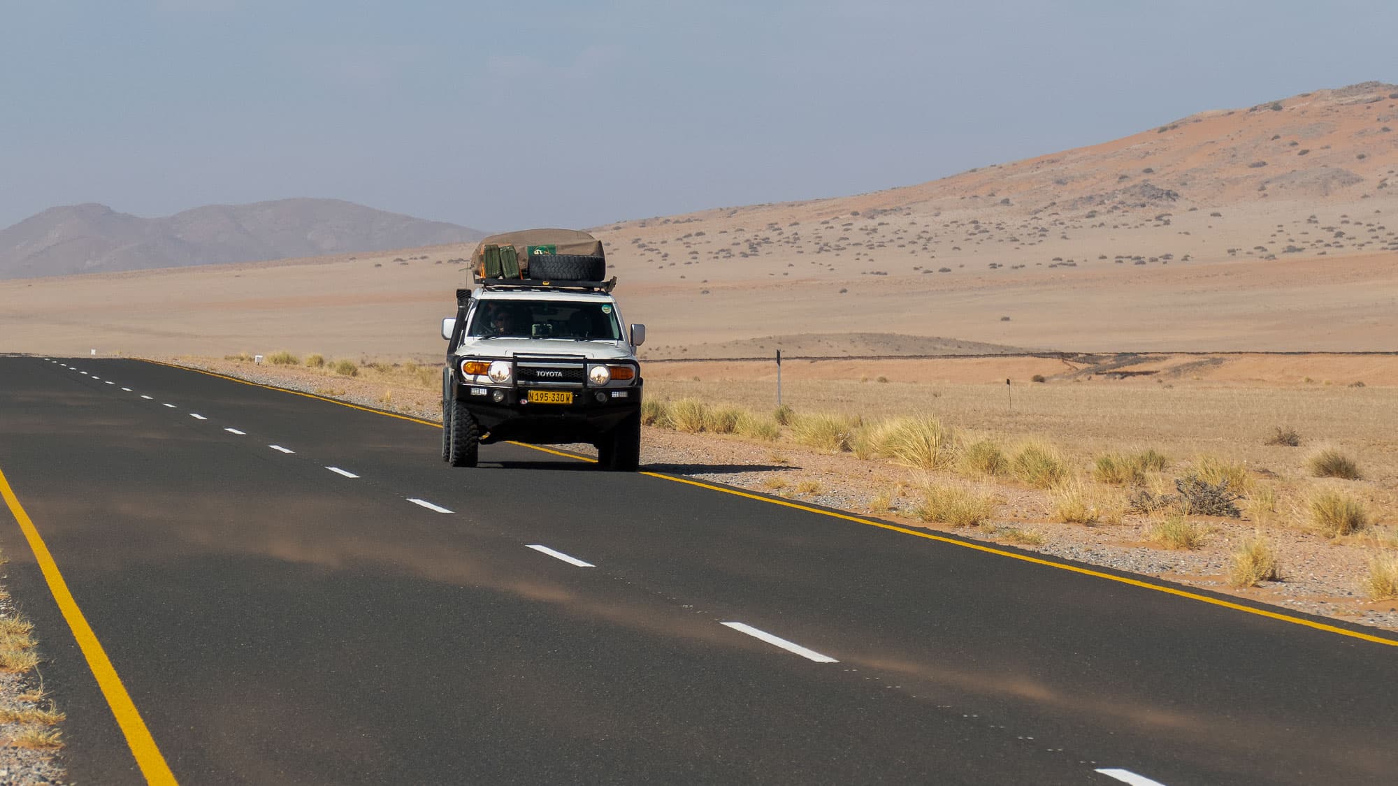 Auf dem Weg nach Lüderitz wird schon die Fahrt zum Erlebnis: Ein voll beladener Geländewagen zieht durch eine Landschaft aus Wüste, Bergen und grenzenloser Straße.