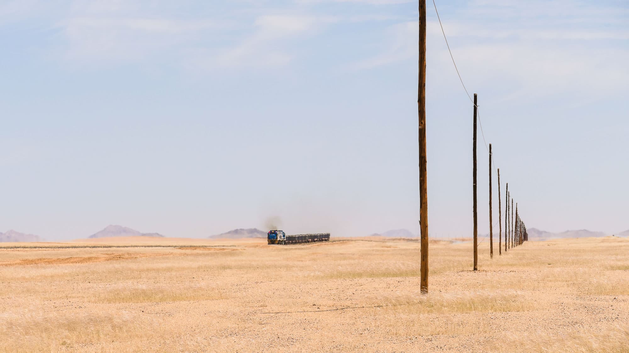 Strommasten und ein einzelner Lastwagen begleiten die einsame Strecke nach Lüderitz - eine Straße, die mitten durch die große Leere führt.