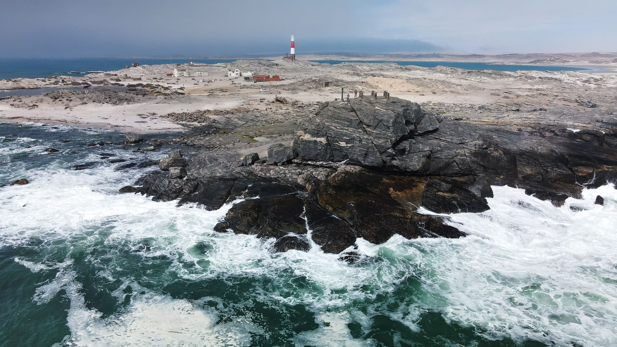 Am Diaz Point bei Lüderitz trifft die raue Brandung des Atlantiks auf schwarze Felsen und den markanten rot-weißen Leuchtturm.