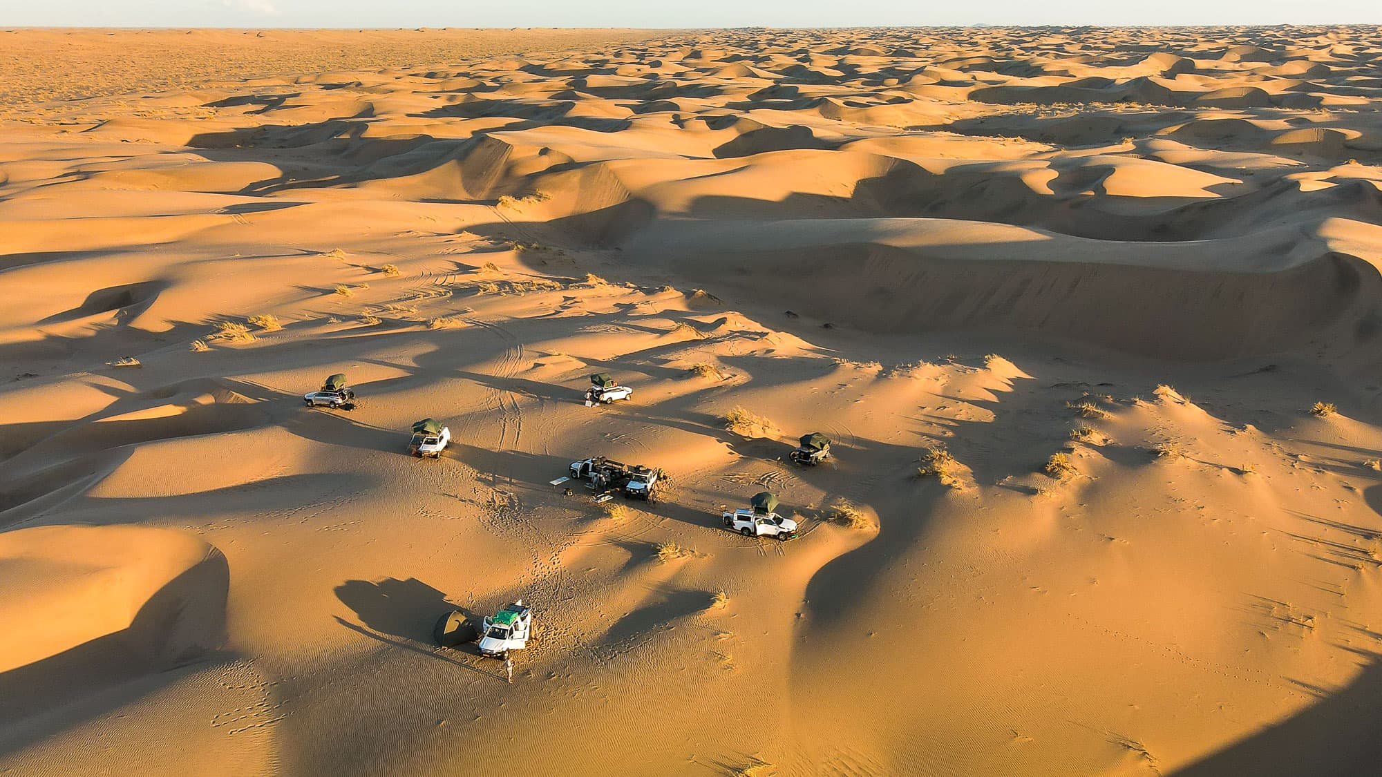Wildcamping mitten in der Namib: Auf der geführten Offroad-Tour von Lüderitz nach Walvis Bay stehen die Fahrzeuge zwischen endlosen Dünen - weiter weg vom Alltag geht kaum.