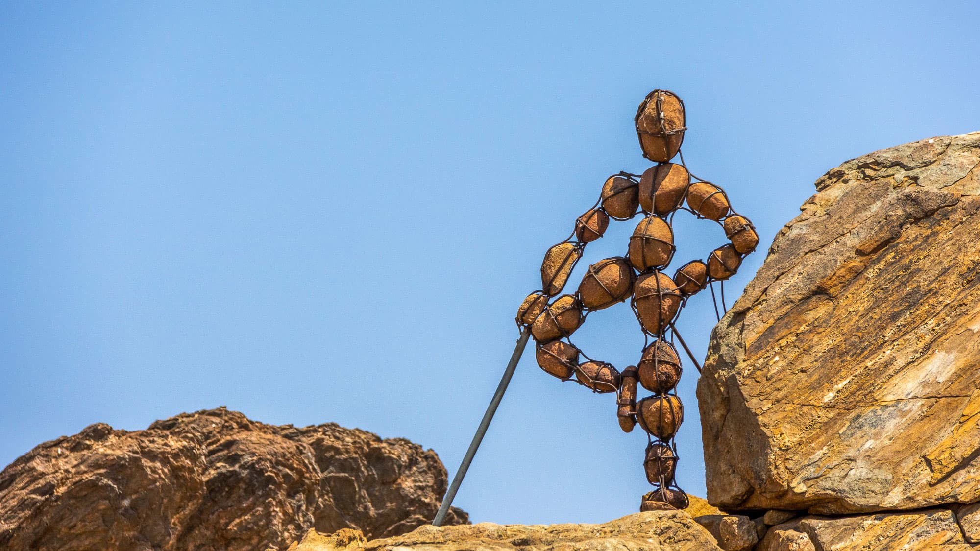 Einer der geheimnisvollen Lone Men of Kaokoland schreitet durch die Felslandschaft im Nordwesten Namibias - steinerne Kunst mitten in der Wildnis.