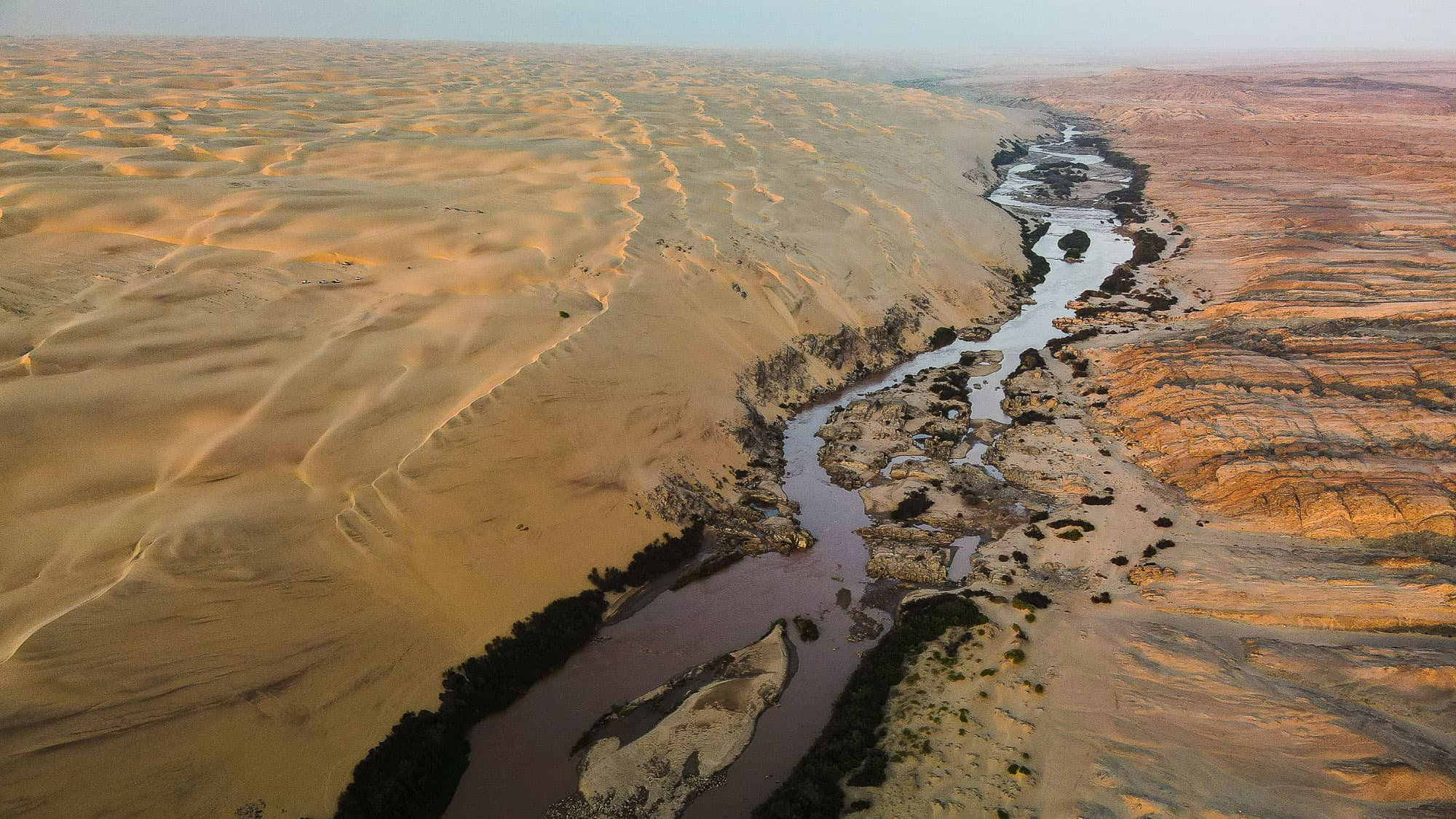 Der Kunene zieht eine spektakuläre Grenze durch die Wüste: links die Sanddünen Namibias, rechts die zerklüftete Felslandschaft Angolas.